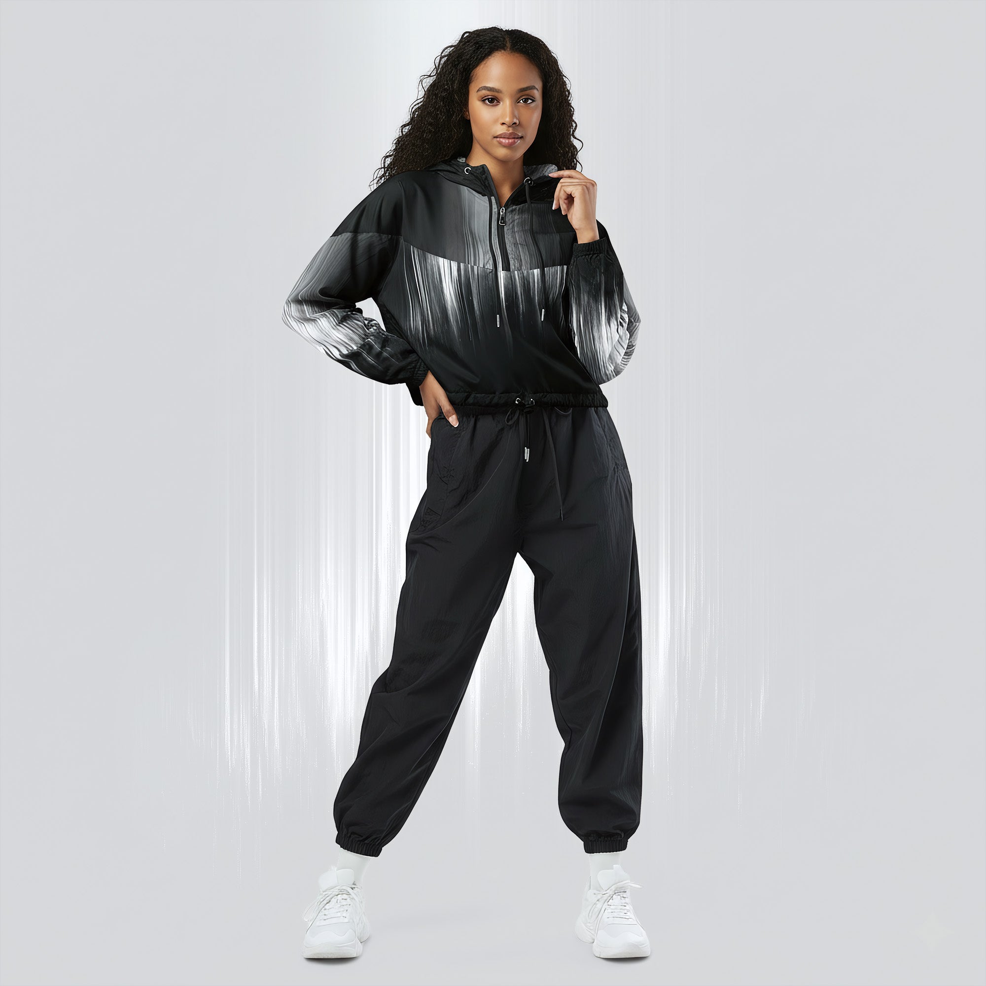 Full‑body view of a model standing in the HER Cropped Dither Distortion Windbreaker (No.02). The hooded jacket, with its abstract black‑to‑white gradient print and half‑zip closure, is worn with black trousers and white shoes. The scene has a minimalist grey background