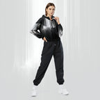 Full‑body view of a model standing in the HER Cropped Dither Distortion Windbreaker (No.06). The hooded jacket, with its abstract black‑to‑white gradient print and half‑zip closure, is worn with black trousers and white shoes. The scene has a minimalist grey background