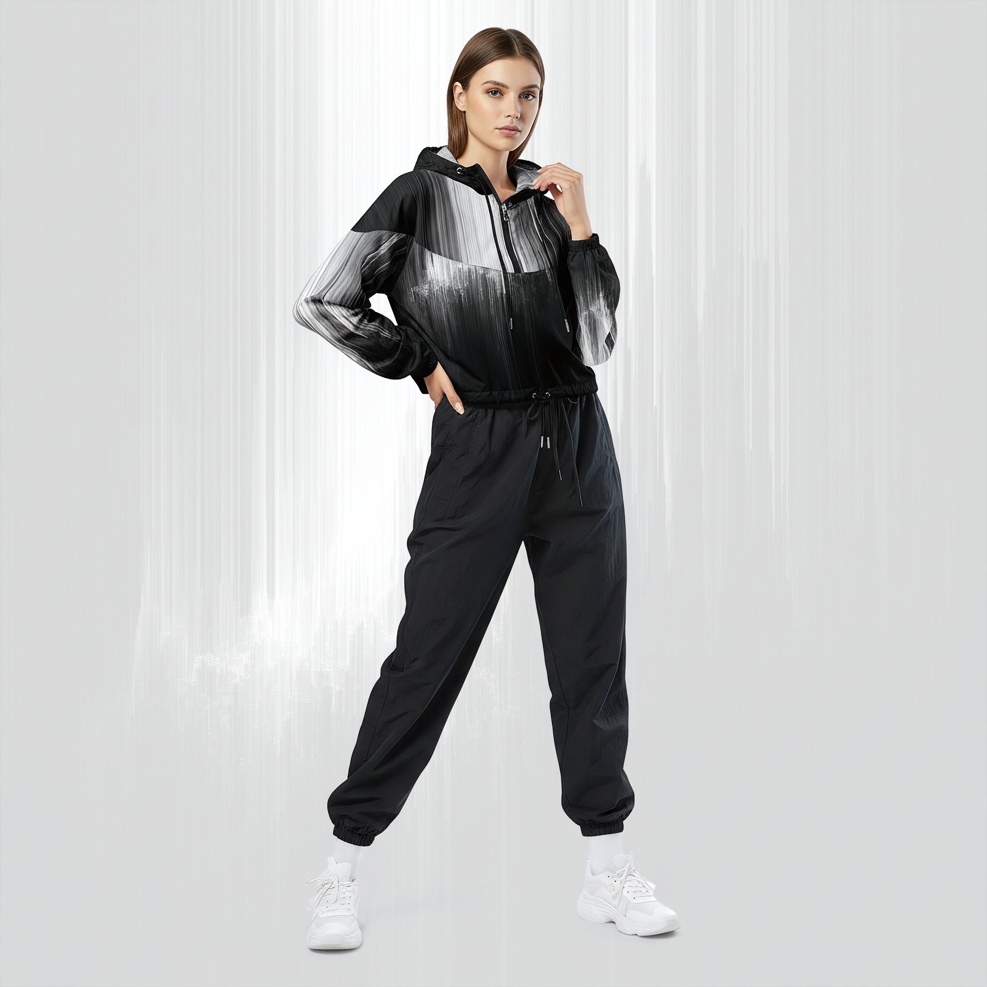 Full‑body view of a model standing in the HER Cropped Dither Distortion Windbreaker (No.06). The hooded jacket, with its abstract black‑to‑white gradient print and half‑zip closure, is worn with black trousers and white shoes. The scene has a minimalist grey background