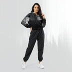 Full‑body view of a model standing in the HER Cropped Dither Distortion Windbreaker (No.10). The hooded jacket, with its abstract black‑to‑white gradient print and half‑zip closure, is worn with black trousers and white shoes. The scene has a minimalist grey background