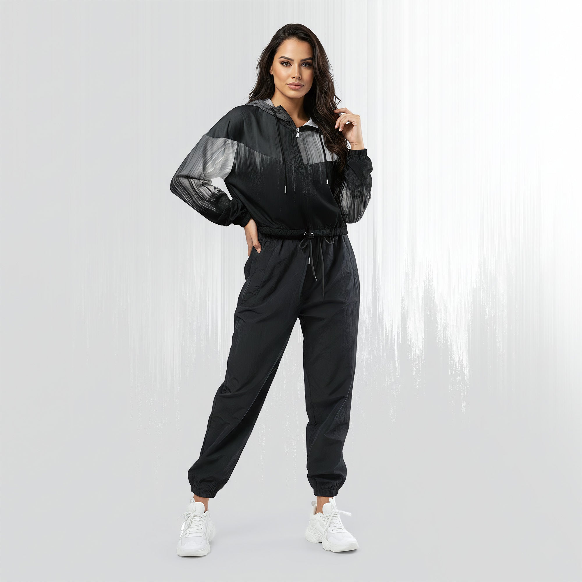 Full‑body view of a model standing in the HER Cropped Dither Distortion Windbreaker (No.10). The hooded jacket, with its abstract black‑to‑white gradient print and half‑zip closure, is worn with black trousers and white shoes. The scene has a minimalist grey background