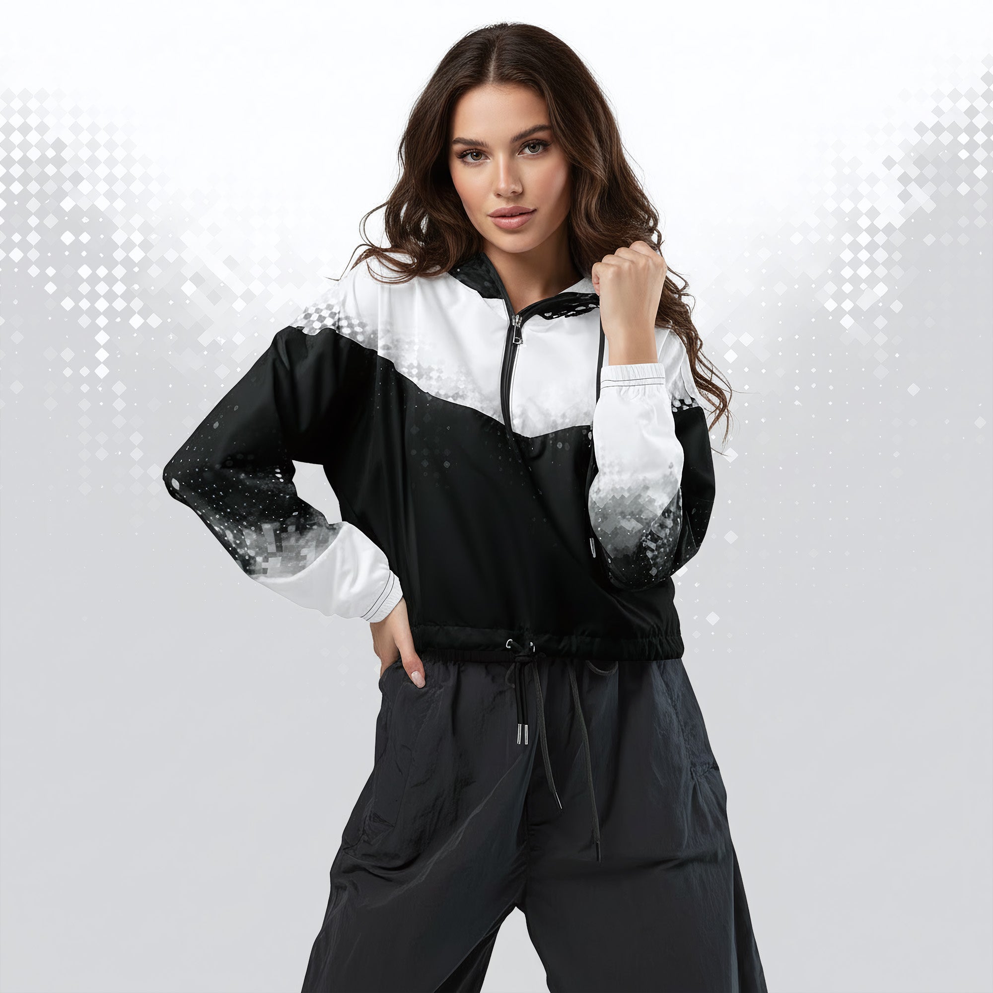 A woman modeling a black and white color-blocked zip-up windbreaker jacket with gradient sleeve details, paired with dark gray drawstring pants, against a light gray background with subtle digital diamond patterns.