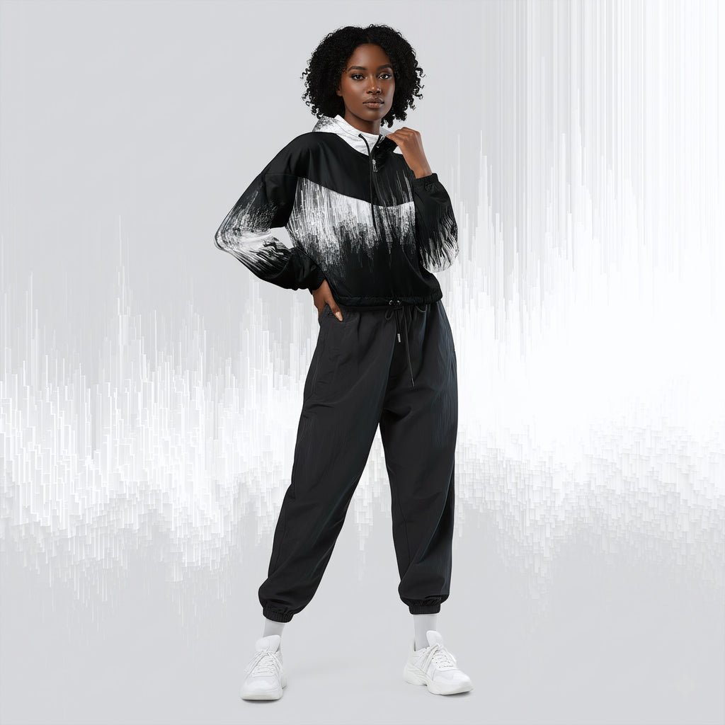 A model wearing a black and white abstract-patterned zip-up hoodie with black jogger pants and white sneakers, standing against a light gray background with vertical white streaks.