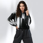 A woman modeling a black, white, and gray striped zip-up jacket with matching dark gray pants, standing against a light gray studio background.