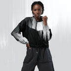 A model wearing a black, white, and gray color-blocked zip-up jacket with matching dark gray pants, posing against a light gray studio background with vertical light streaks.