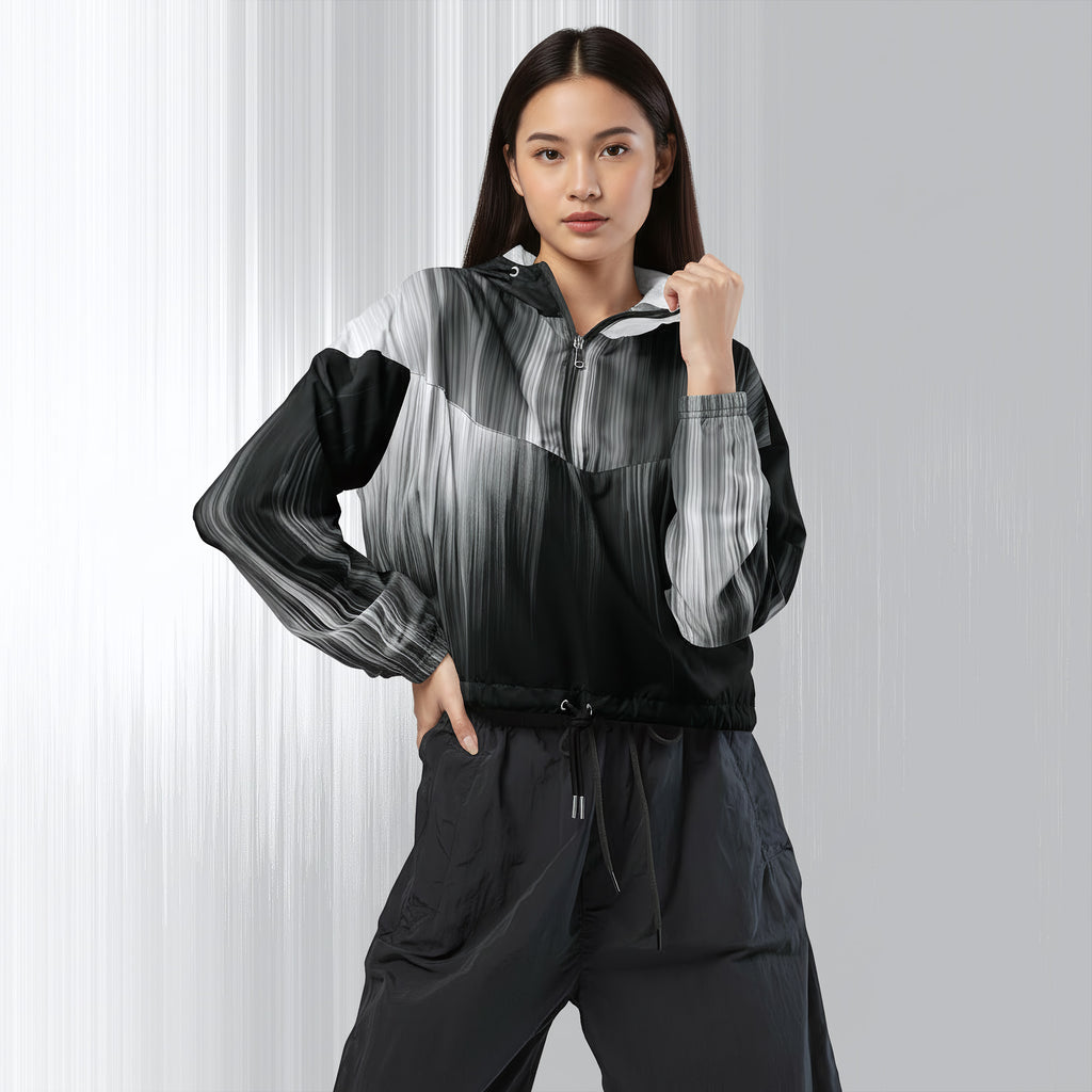 A woman modeling a lightweight zip-front jacket with a black, gray, and white abstract gradient pattern, paired with dark gray pants, against a light gray studio background.