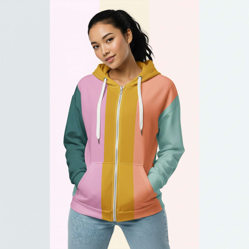 Front view of another woman wearing the Her Palette Strip Hoodie No. 12; pastel stripes cover the torso and sleeves, lavender hood lining and white zip, hands resting in the kangaroo pocket, pastel striped background from Form Finding Design.