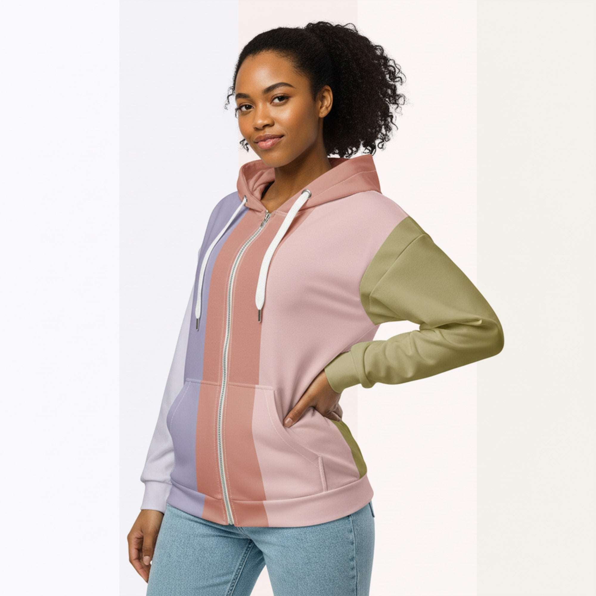 Front view of another woman wearing the Her Palette Strip Hoodie No. 18; pastel stripes cover the torso and sleeves, lavender hood lining and white zip, hands resting in the kangaroo pocket, pastel striped background from Form Finding Design.