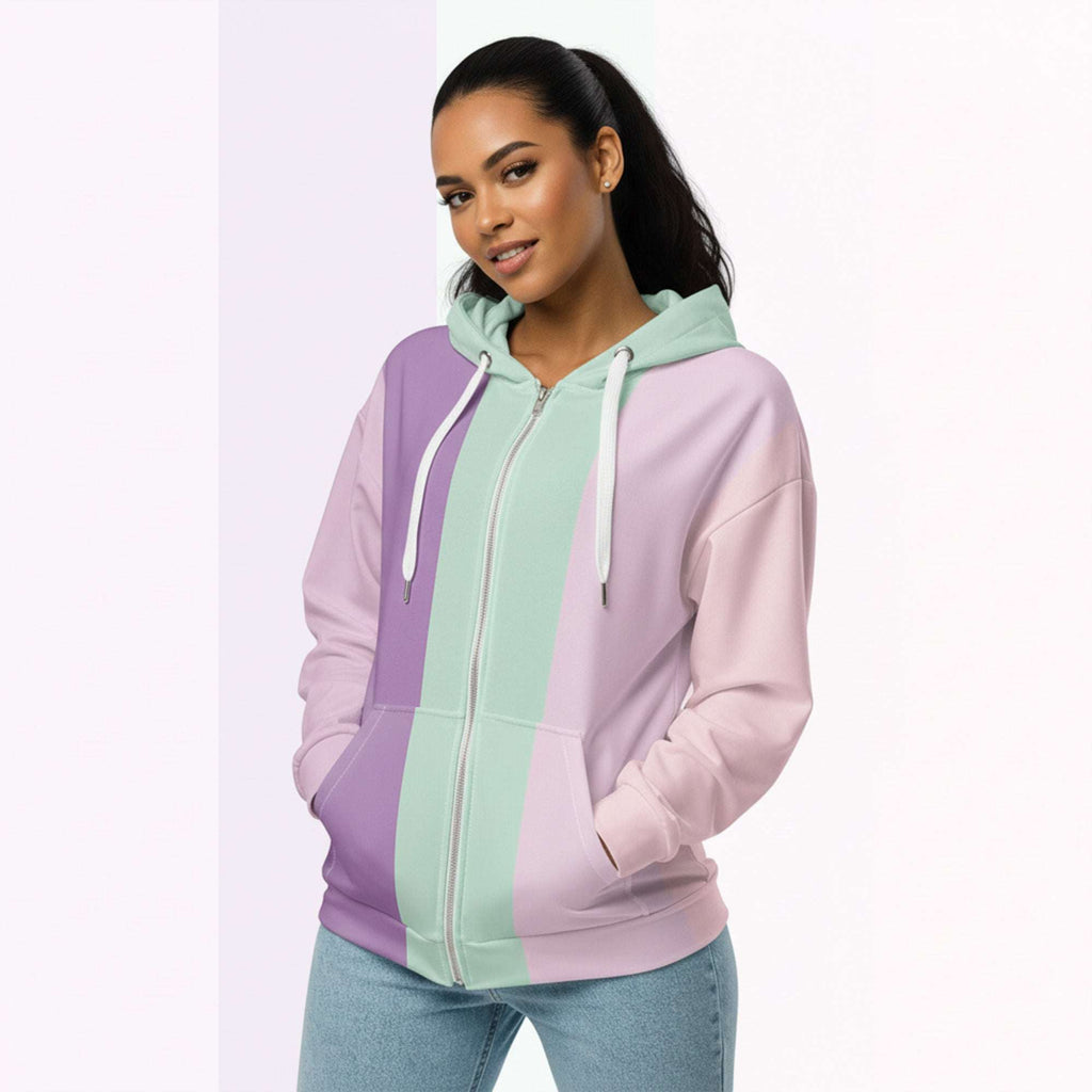 Front view of another woman wearing the Her Palette Strip Hoodie No. 19; pastel stripes cover the torso and sleeves, lavender hood lining and white zip, hands resting in the kangaroo pocket, pastel striped background from Form Finding Design.