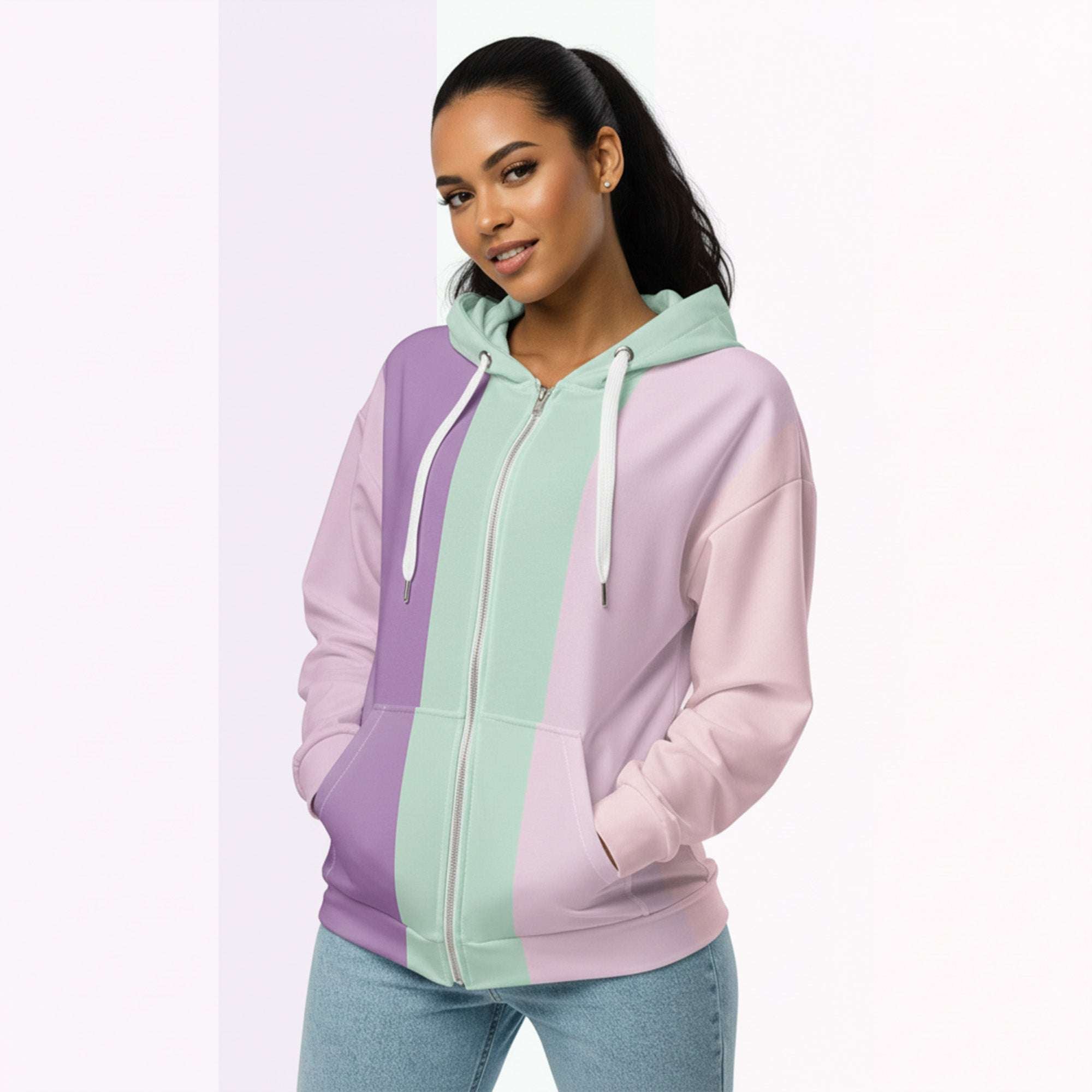 Front view of another woman wearing the Her Palette Strip Hoodie No. 19; pastel stripes cover the torso and sleeves, lavender hood lining and white zip, hands resting in the kangaroo pocket, pastel striped background from Form Finding Design.