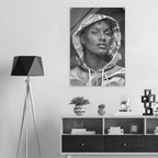 A black and white wall art print depicting a woman in a hoodie, displayed in a modern room setting above a wooden shelf with decorative items.