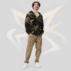 Male model wearing the Form Finding Design men’s Shadow Drip Hoodie (No.06) with the zip partly undone over a light‑coloured tee; the black hoodie’s earth‑toned abstract shapes stand out against khaki cargo trousers, as he poses with hands in his pockets on a pale grey background with faint arc motifs.