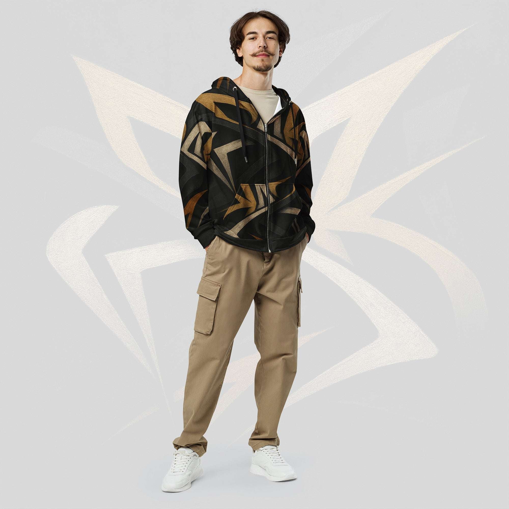 Male model wearing the Form Finding Design men’s Shadow Drip Hoodie (No.06) with the zip partly undone over a light‑coloured tee; the black hoodie’s earth‑toned abstract shapes stand out against khaki cargo trousers, as he poses with hands in his pockets on a pale grey background with faint arc motifs.