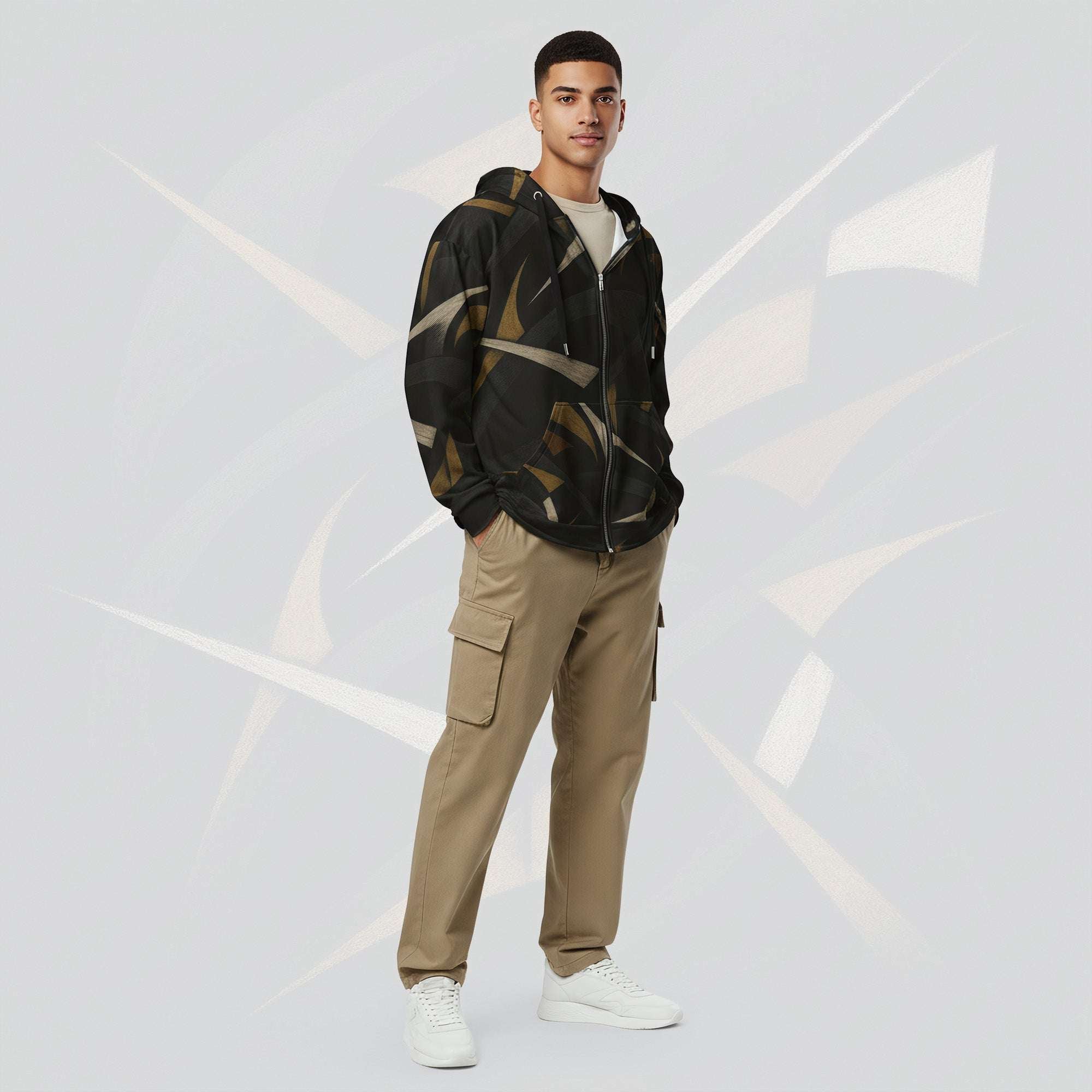 Front portrait of a male model wearing the Form Finding Design men’s Shadow Drip Hoodie (No.10), zipped up and hands by his sides; the hoodie’s abstract tan and olive print contrasts with his khaki cargo trousers, set against a pale grey background with faint curved motifs.
