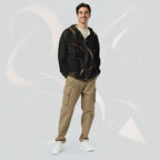 Front portrait of a male model wearing the Form Finding Design men’s Shadow Drip Hoodie (No.15), zipped up and hands by his sides; the hoodie’s abstract tan and olive print contrasts with his khaki cargo trousers, set against a pale grey background with faint curved motifs.