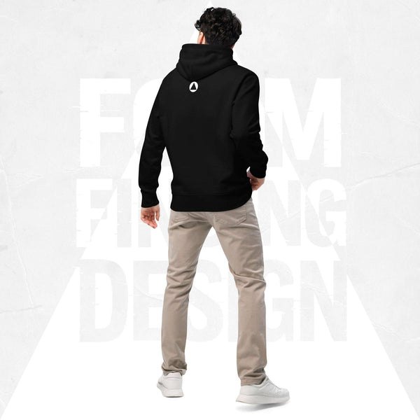Back view on model in Form Finding Design Men’s Signature Hoodie (FFD-12), black—minimal back with small white circular emblem below the hood, paired with beige chinos and white trainers.