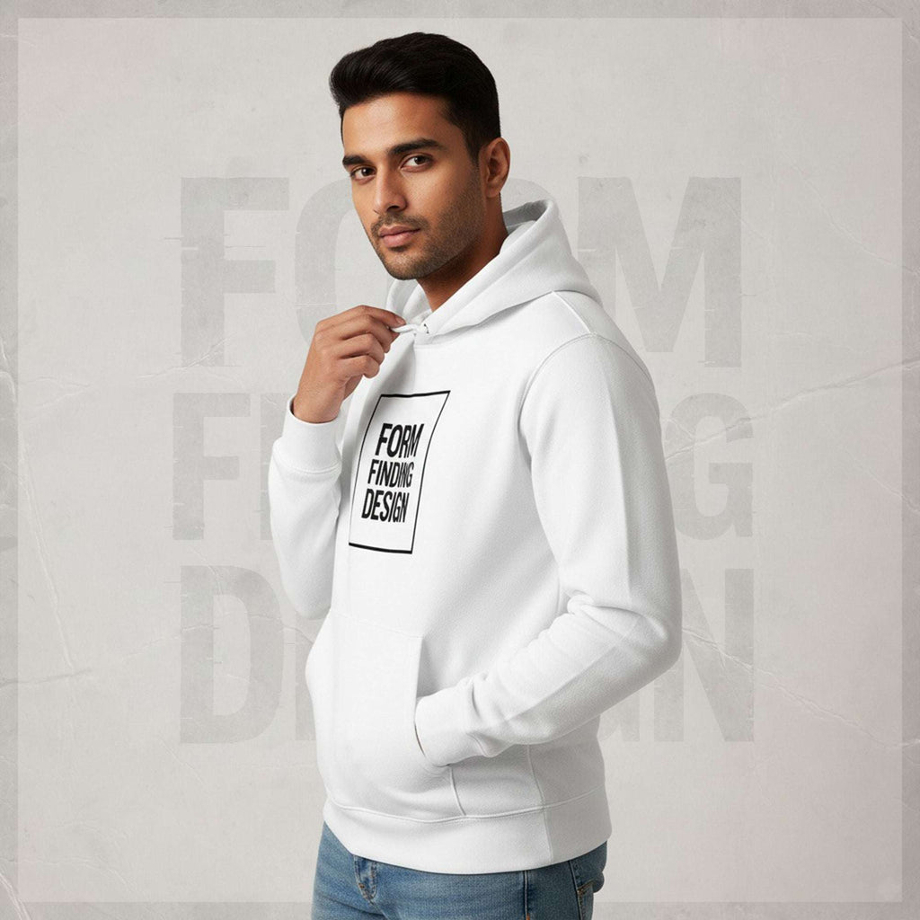 Three-quarter lifestyle shot of model in FormFD Men’s Signature Hoodie (FFD-17), white—black square “FORM FINDING DESIGN” chest print, hands in pockets, blue jeans, minimalist editorial background.