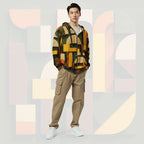 Male model wearing Form Finding Design Men’s Urban Utility Hoodie (No.04), front lifestyle portrait—earth-inspired geometric block print zip hoodie with kangaroo pockets and black drawstrings, styled with tan cargo trousers, minimalist architectural background.