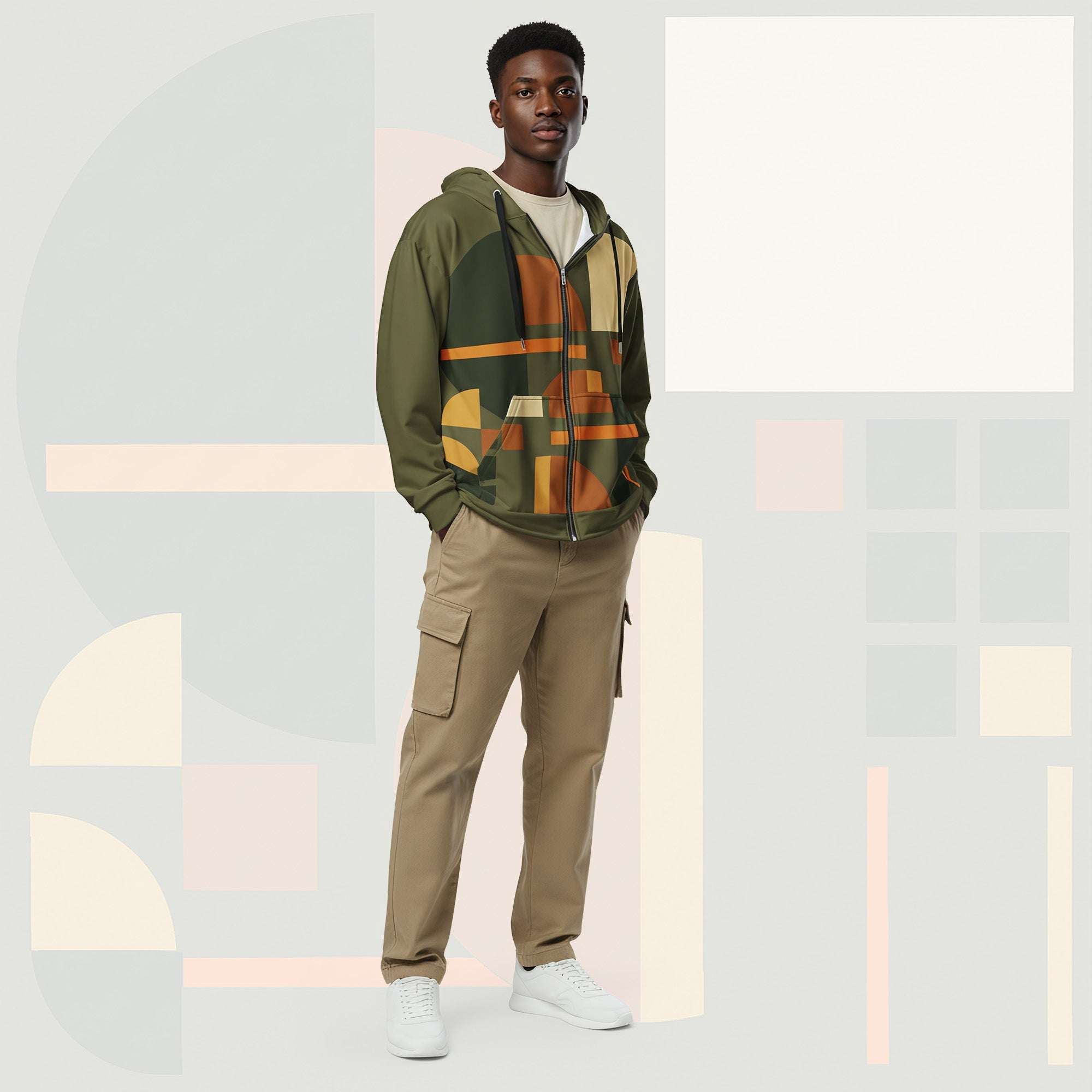 Male model wearing Form Finding Design Men’s Urban Utility Hoodie (No.12), front lifestyle portrait—earth-inspired geometric block print zip hoodie with kangaroo pockets and black drawstrings, styled with tan cargo trousers, minimalist architectural background.