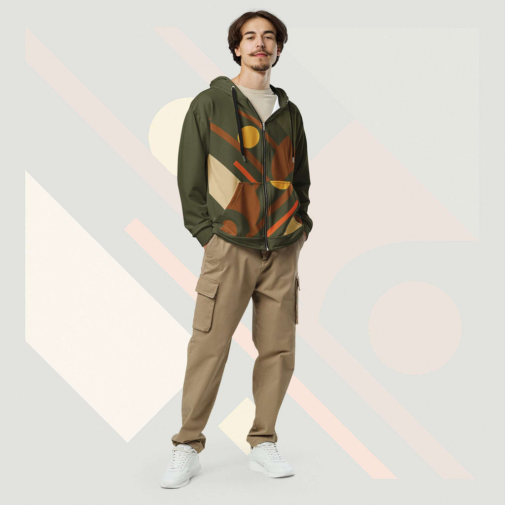 Male model wearing Form Finding Design Men’s Urban Utility Hoodie (No.14), front full-body—earth-tone geometric print zip hoodie with black drawstrings, styled with tan cargo trousers and white trainers, minimal architectural studio backdrop.