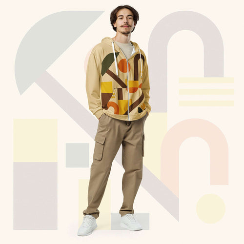 Male model wearing Form Finding Design Men’s Urban Utility Hoodie (No.16), front full-body—earth-tone geometric print zip hoodie with black drawstrings, styled with tan cargo trousers and white trainers, minimal architectural studio backdrop.