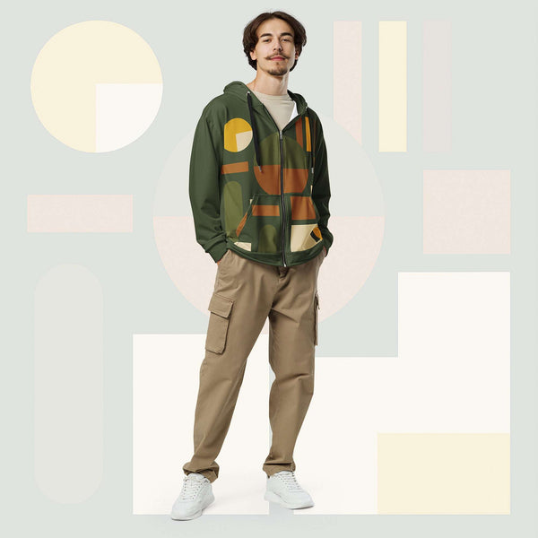 Male model wearing Form Finding Design Men’s Urban Utility Hoodie (No.20), front full-body—earth-tone geometric print zip hoodie with black drawstrings, styled with tan cargo trousers and white trainers, minimal architectural studio backdrop.