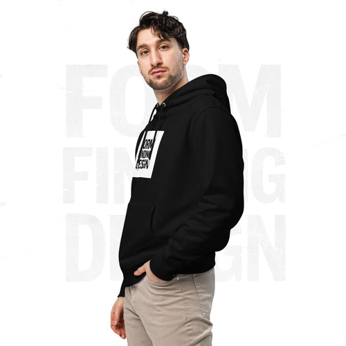 Three-quarter side portrait of male model in FormFD Men’s Signature Hoodie (FFD-14), black—hood drape, kangaroo pocket and partial chest logo visible, hand in pocket, beige chinos.