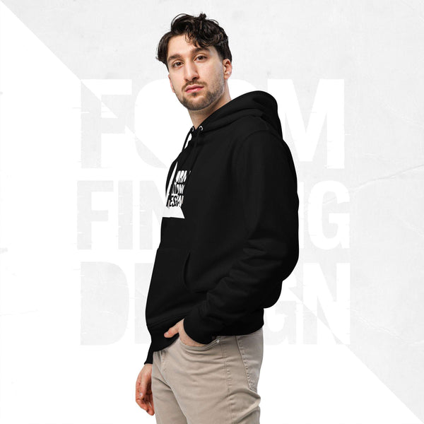 Three-quarter side portrait of male model in FormFD Men’s Signature Hoodie (FFD-16), black—hood drape, kangaroo pocket and partial chest logo visible, hand in pocket, beige chinos.