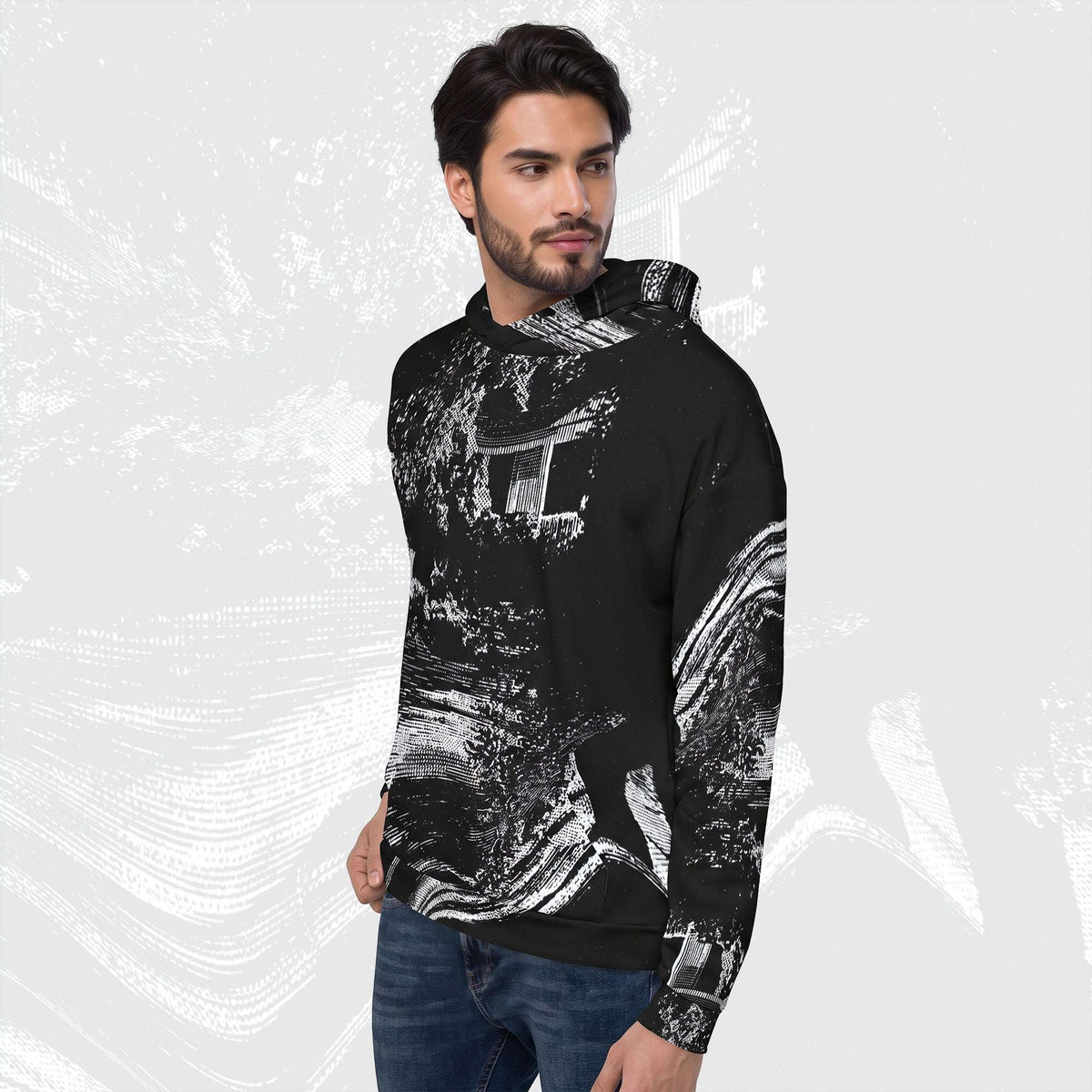 A man wearing a black pullover hoodie with a white abstract brushstroke pattern, paired with blue jeans, set against a light gray background with white textured strokes.