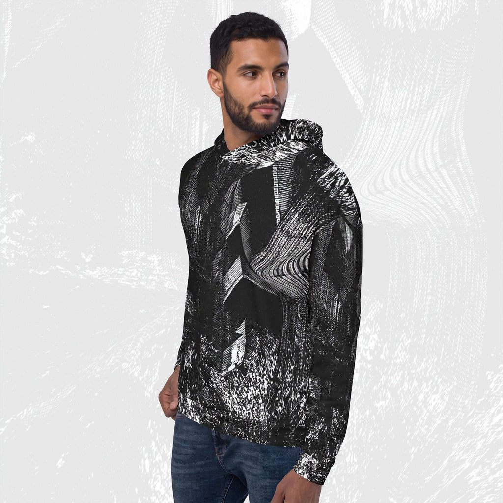A man wearing a black and white abstract patterned hoodie with blue jeans, standing against a light gray textured background.