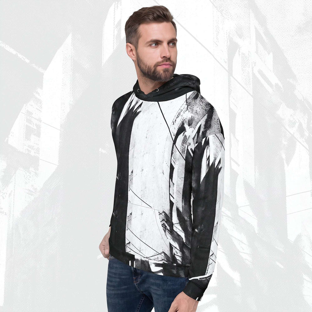 A man wearing a black and white abstract print hoodie with blue jeans, standing against a light gray background with a faint cityscape pattern.