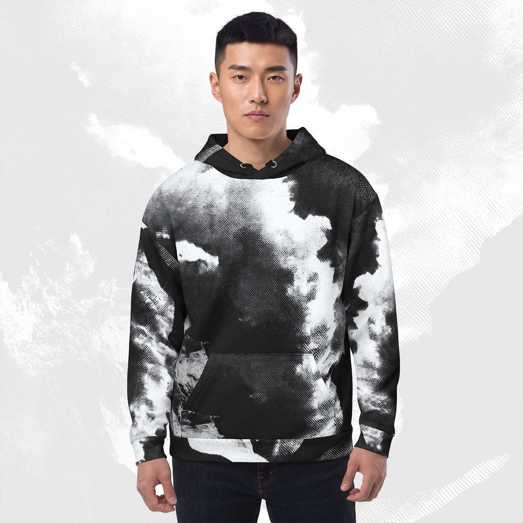 A man wearing a black hoodie with a white and gray abstract brushstroke pattern, paired with blue jeans, set against a light gray textured background.