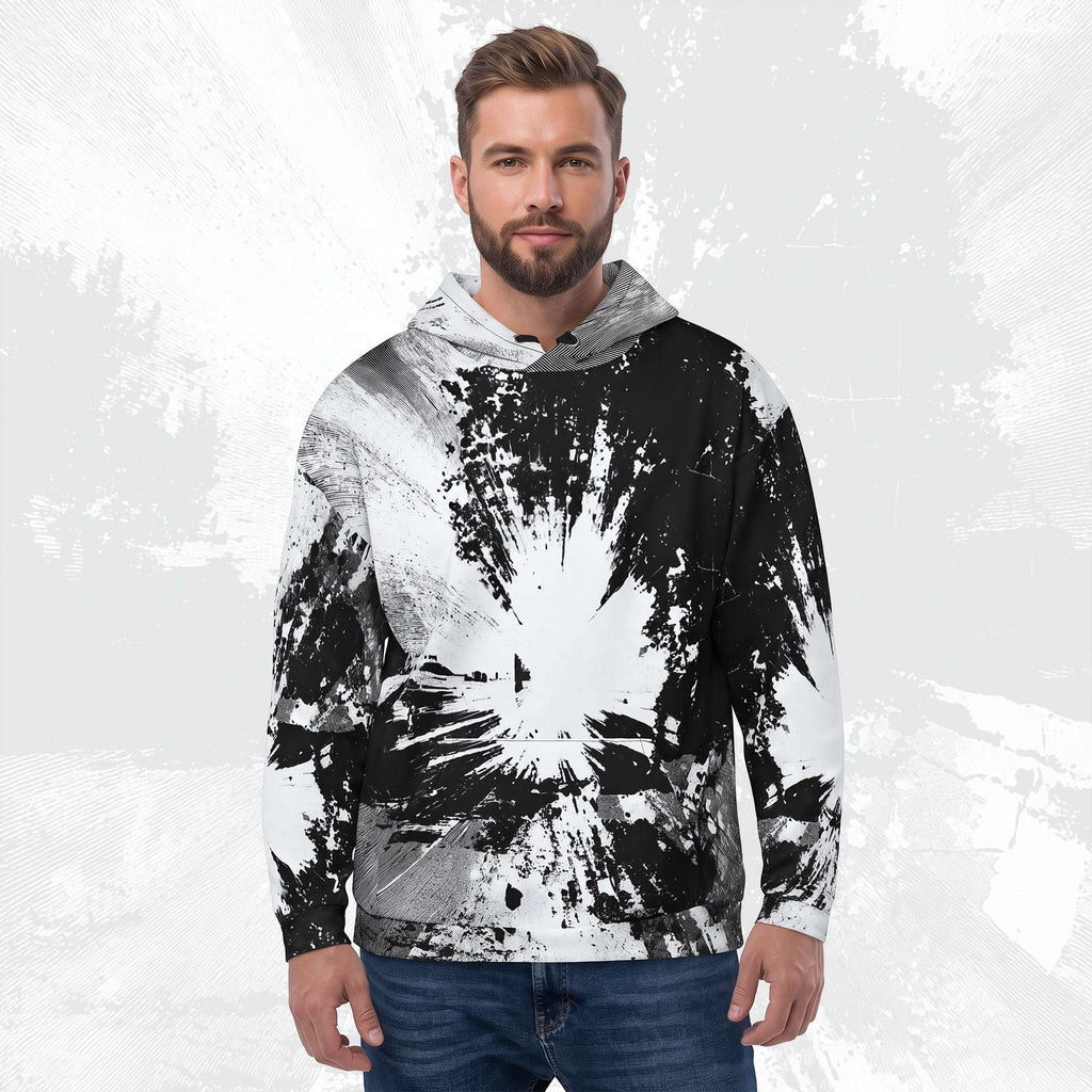 A man wearing a black and white abstract splatter-patterned hoodie, paired with blue jeans, standing against a textured light gray background.