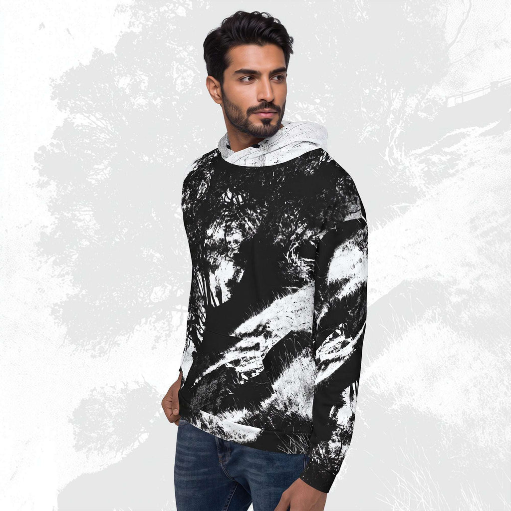 A man wearing a black and white abstract patterned hoodie with a white hood lining, paired with blue jeans, set against a textured light gray background.