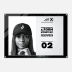 A black-framed acrylic wall art print featuring a black-and-white portrait of a woman wearing a cap on the left, with text on the right reading 'UNDER ARMOUR x FORM FUNDAMENTALS STAMP CAP' and '02'.