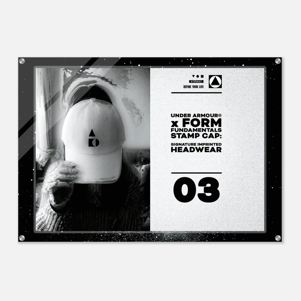 A rectangular acrylic wall art print with rounded corners and visible mounting hardware, featuring a black-and-white split design. The left side shows a monochrome photo of a person wearing a white cap, and the right side contains product text reading 'UNDER ARMOUR x FORM FUNDAMENTALS STAMP CAP' and '03'.