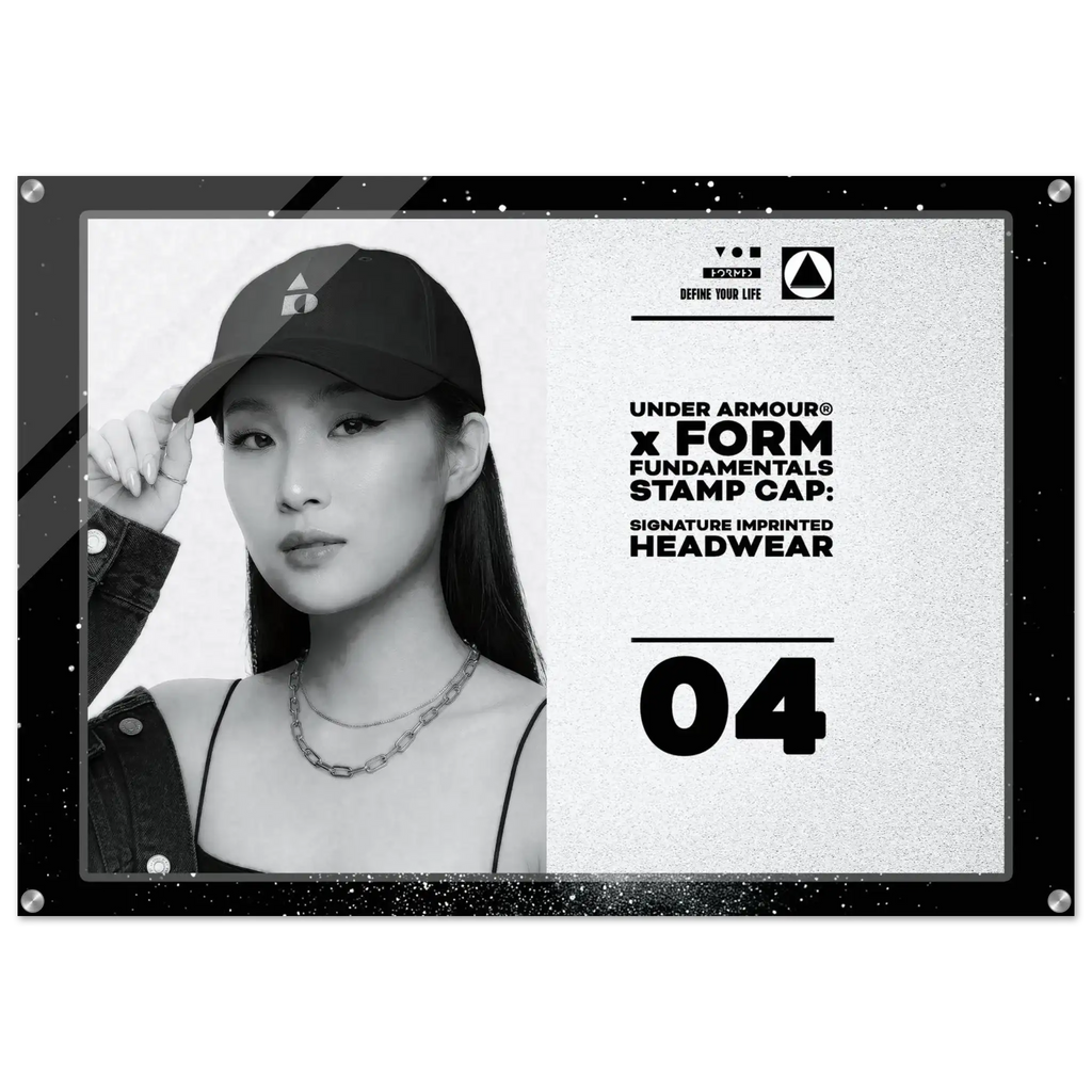 A rectangular black-framed print or poster featuring a black-and-white portrait of a woman in a cap, alongside text reading 'UNDER ARMOUR x FORM FUNDAMENTALS STAMP CAP: SIGNATURE IMPRINTED HEADWEAR' and the number '04'.