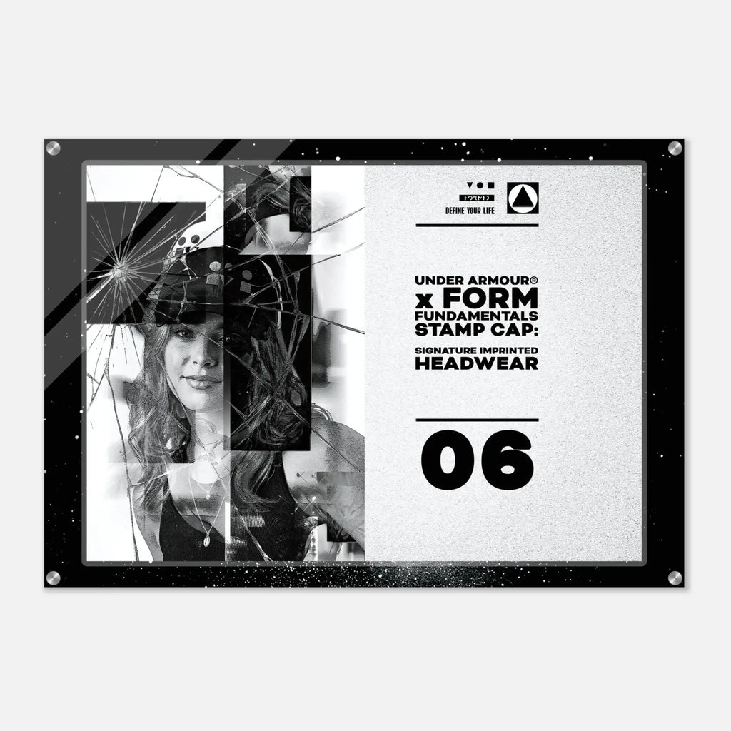 A rectangular acrylic wall art print with a black frame and silver corner hardware, featuring a black-and-white graphic design with text reading 'UNDER ARMOUR x FORM FUNDAMENTALS STAMP CAP: SIGNATURE IMPRINTED HEADWEAR' and the number '06'.