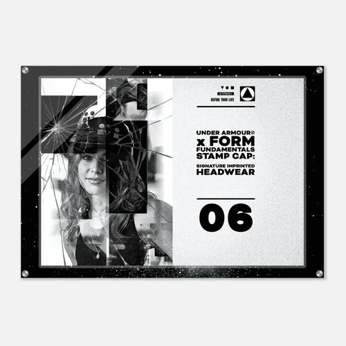 A rectangular acrylic wall art print with a black frame and silver corner hardware, featuring a black-and-white graphic design with text reading 'UNDER ARMOUR x FORM FUNDAMENTALS STAMP CAP: SIGNATURE IMPRINTED HEADWEAR' and the number '06'.
