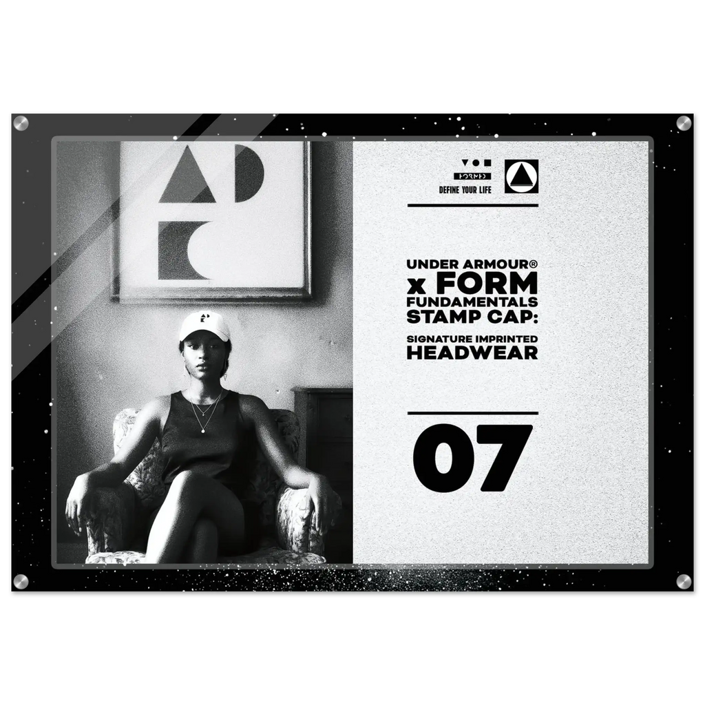 A rectangular black stamp cap plaque featuring a black-and-white photo of a seated woman on the left and printed text on the right, including 'UNDER ARMOUR x FORM FUNDAMENTALS STAMP CAP' and '07'.