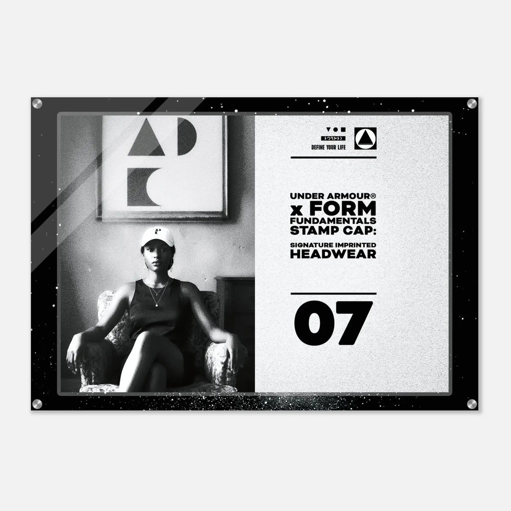 A rectangular black-framed wall art print with a split design: the left side shows a black-and-white photo of a seated woman wearing a cap, and the right side has a light textured background with Under Armour branding, text reading 'FORM FUNDAMENTALS STAMP CAP,' and the number 07.