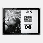 A rectangular Under Armour headwear display sign or poster with a black frame, showing a black-and-white photo of a woman wearing a cap on the left and printed text on the right including 'UNDER ARMOUR x FORM FUNDAMENTALS STAMP CAP' and the number '08'.