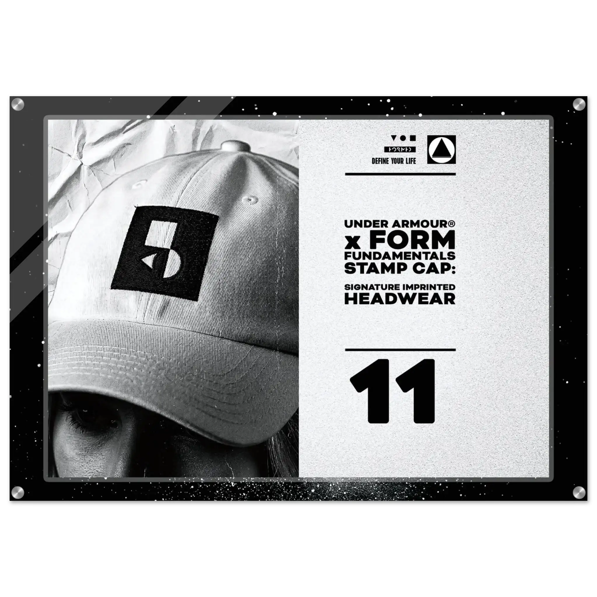 A framed black-and-white promotional print featuring a close-up of a person wearing a baseball cap with a large Under Armour stamp logo. The right side includes text reading 'UNDER ARMOUR x FORM FUNDAMENTAL STAMP CAP: SIGNATURE IMPRINTED HEADWEAR' and the number 11.