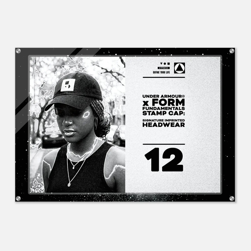 A black and white Under Armour x Form Fundamentals stamp cap design poster or print, featuring a black-and-white portrait of a woman wearing a cap on the left and product text including 'UNDER ARMOUR x FORM FUNDAMENTALS STAMP CAP' and 'SIGNATURE IMPRINTED HEADWEAR' on the right, all enclosed in a black frame with visible corner hardware.