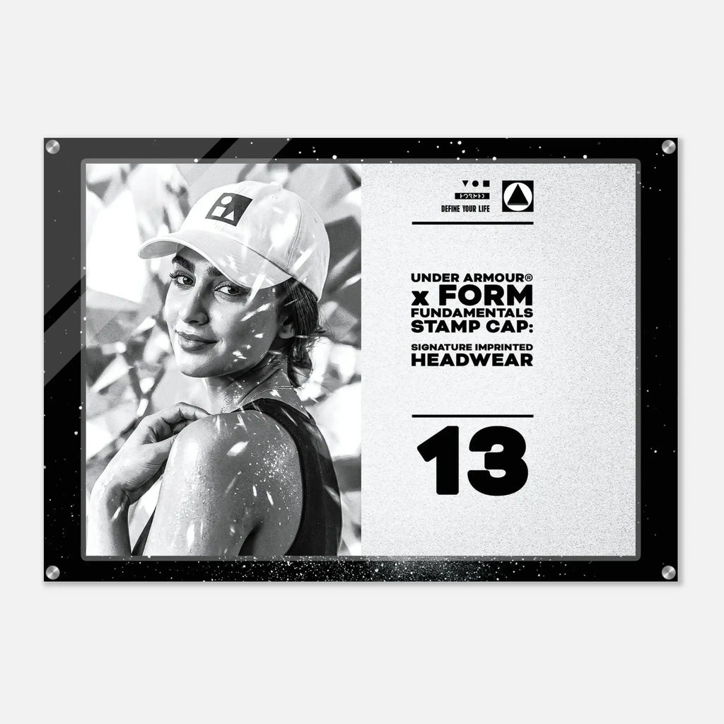 A rectangular Under Armour stamp cap headwear graphic print with a black border, featuring a black-and-white photo of a woman in a cap on the left and product text on the right, including 'UNDER ARMOUR x FORM FUNDAMENTALS STAMP CAP' and 'SIGNATURE IMPRINTED HEADWEAR' with the number 13.