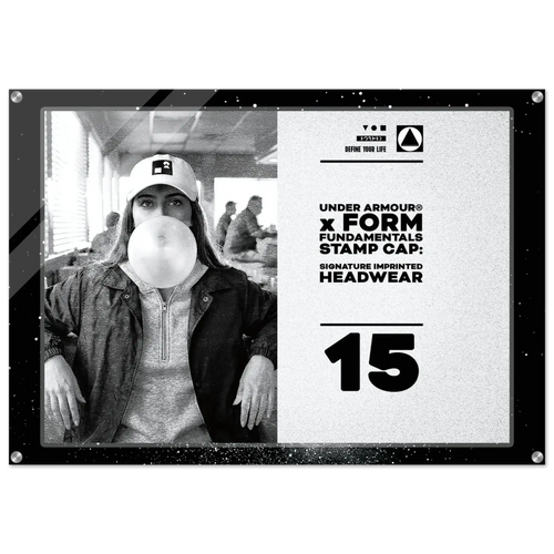 A square promotional display plaque or poster featuring a black-and-white photo of a woman wearing an Under Armour cap and blowing bubble gum, alongside printed text reading 'UNDER ARMOUR x FORM FUNDAMENTALS STAMP CAP: SIGNATURE IMPRINTED HEADWEAR' and the number '15'.