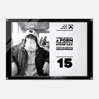 A rectangular acrylic wall art print with rounded corners and visible mounting hardware, featuring a black-and-white photo of a person wearing a cap and blowing a bubble gum bubble, alongside white text reading 'UNDER ARMOUR x FORM FUNDAMENTALS STAMP CAP: SIGNATURE IMPRINTED HEADWEAR' and the number '15'.