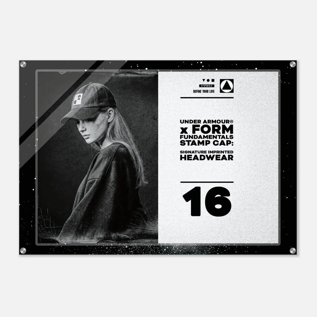 A rectangular acrylic wall art print featuring a black-and-white portrait of a woman wearing a baseball cap on the left, with text on the right that reads 'UNDER ARMOUR x FORM FUNDAMENTALS STAMP CAP' and 'SIGNATURE IMPRINTED HEADWEAR' above a large '16'. The print is shown against a light gray background with a subtle drop shadow.