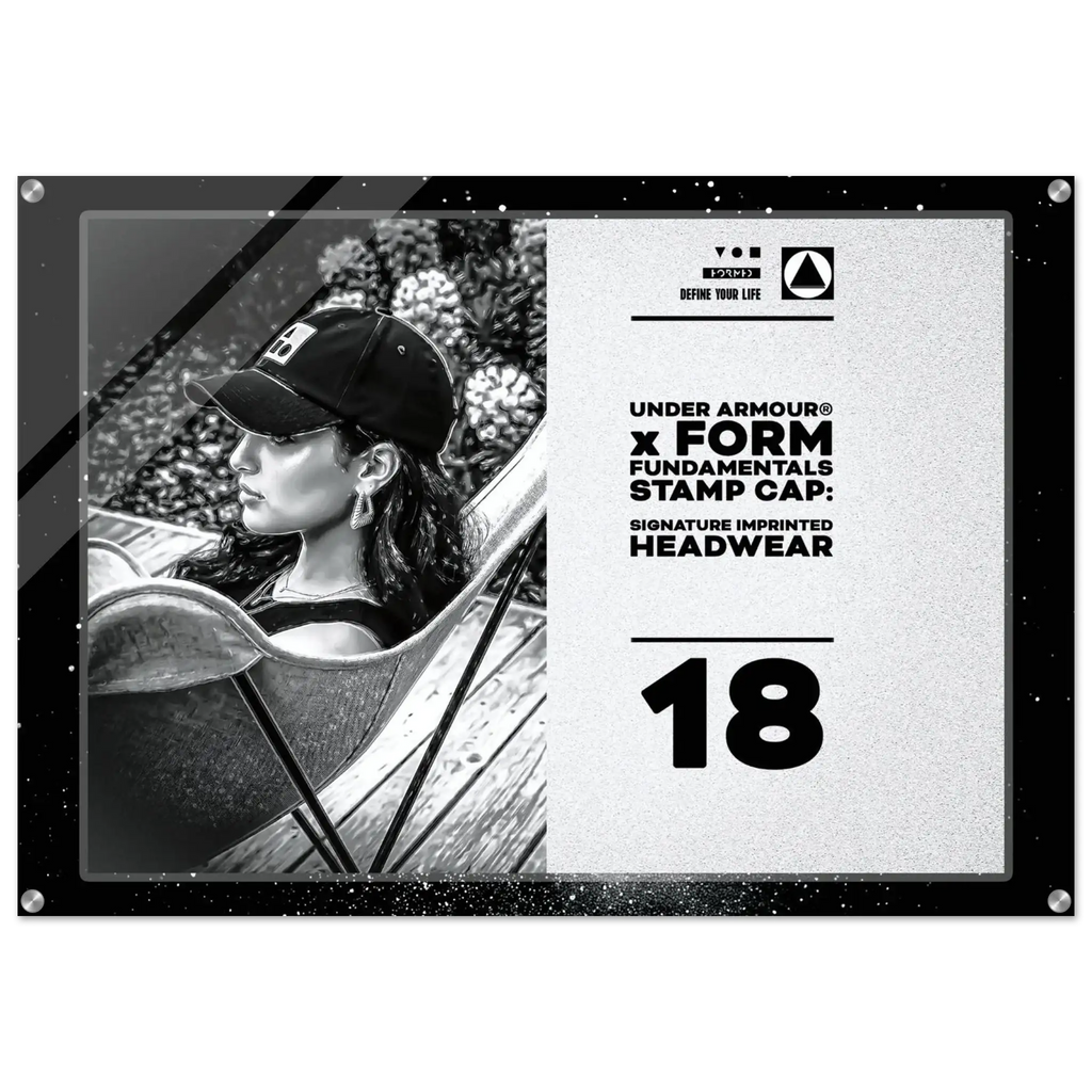 A rectangular acrylic or glass stamp cap plaque featuring a black-and-white photo of a woman wearing a baseball cap on the left, and printed text on the right that reads 'UNDER ARMOUR x FORM FUNDAMENTALS STAMP CAP: SIGNATURE IMPRINTED HEADWEAR' and '18'. The plaque has a black border with corner rivets and is shown against a plain white background.