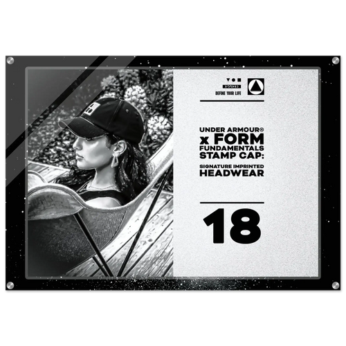 A rectangular acrylic or glass stamp cap plaque featuring a black-and-white photo of a woman wearing a baseball cap on the left, and printed text on the right that reads 'UNDER ARMOUR x FORM FUNDAMENTALS STAMP CAP: SIGNATURE IMPRINTED HEADWEAR' and '18'. The plaque has a black border with corner rivets and is shown against a plain white background.